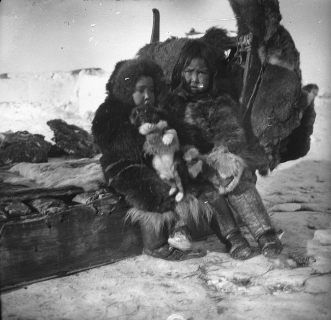 Due bambini sulla slitta il giorno della partenza della spedizione del bicentenario (Jubilæumsekspeditionen, 1920-1923) dopo la sosta a Igdloluorssuit, vicino a Thule Igdloluorssuit, 1921 Fotografo Lauge Koch © Arktisk Institut